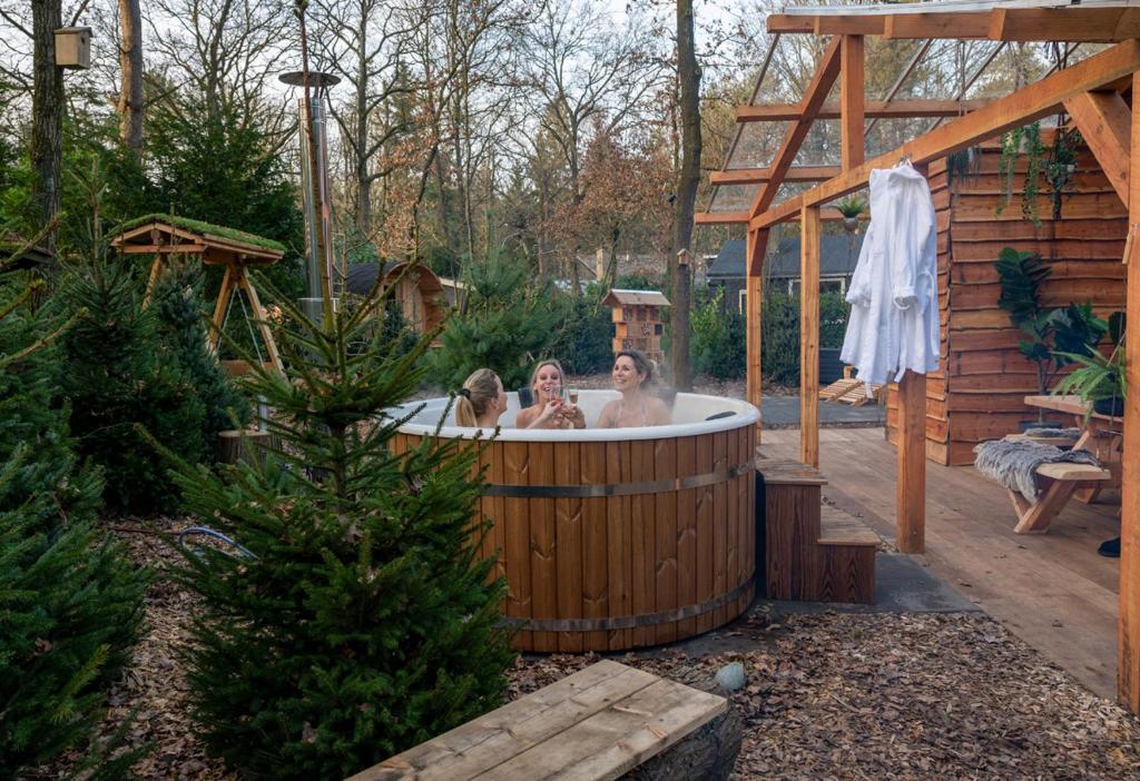 two women in a hot tub in a garden at ZEN-Bungalow NO 3 met sauna en hottub in Rheezerveen