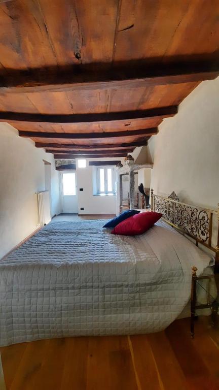 1 dormitorio con 1 cama grande y techo de madera en Casa alla Fontana, en Faggeto Lario 