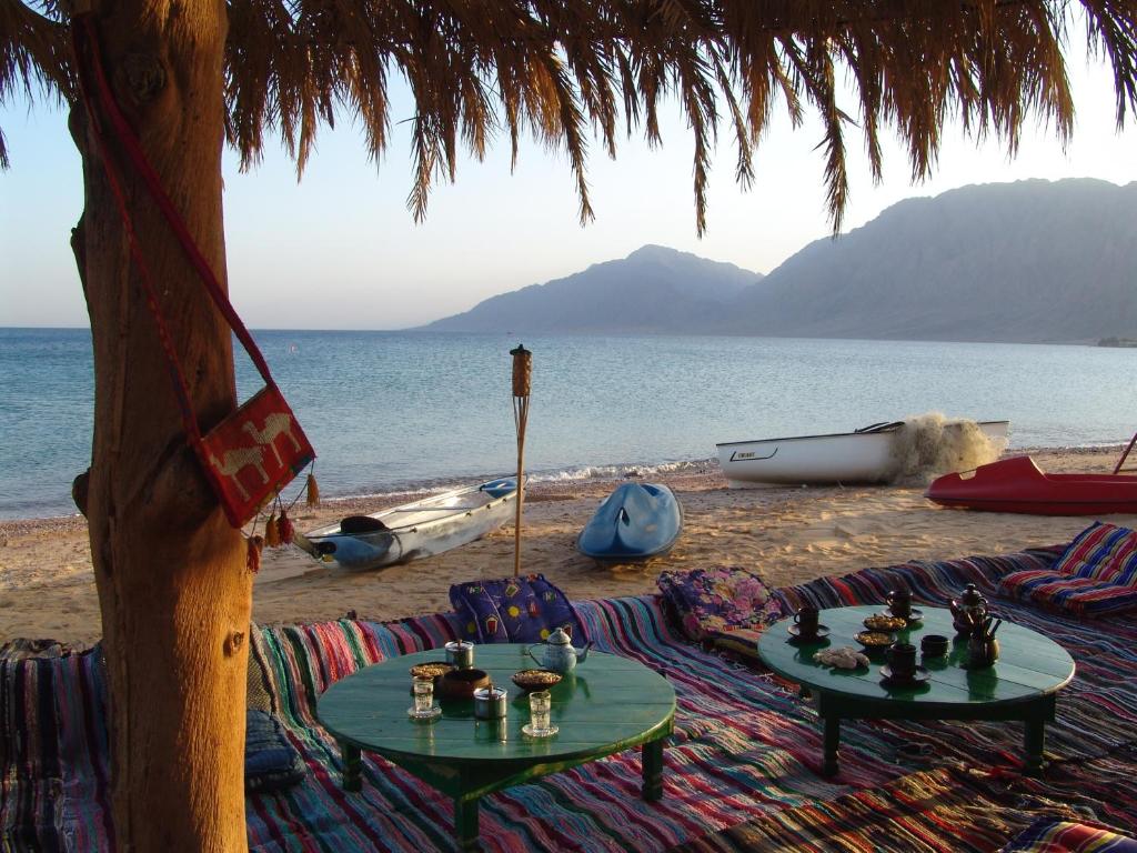 uma praia com duas mesas e cadeiras na praia em Sayadeen Village - Red Sea Riviera em Nuweiba