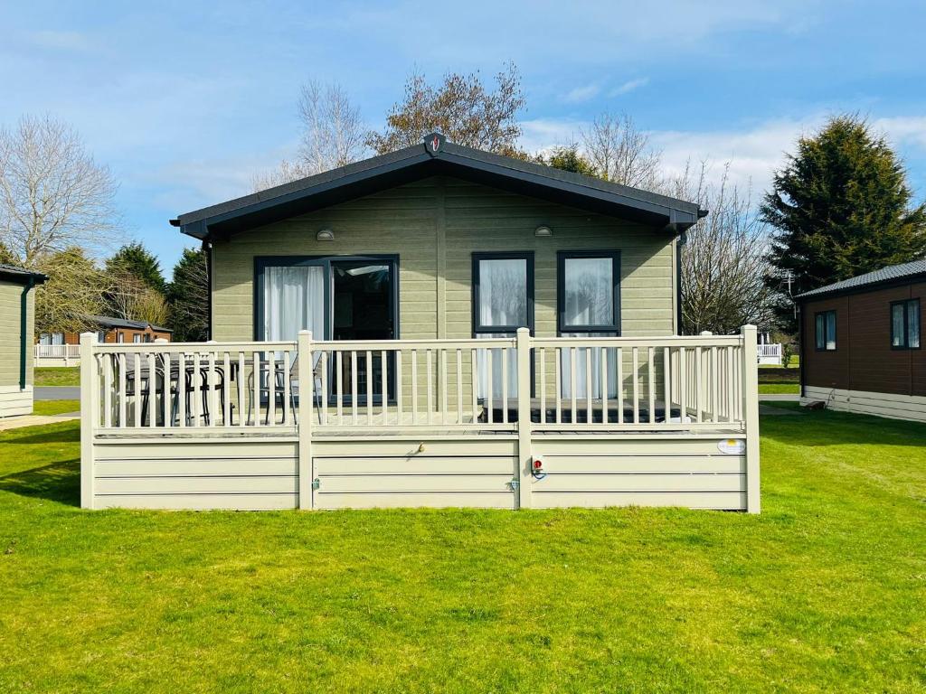 a small house with a white fence in the grass at Audley Lodge with Hot Tub in York