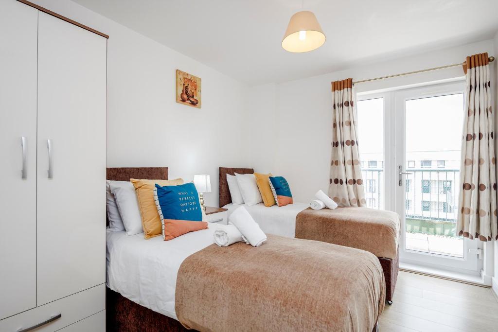 two beds in a white room with a window at Impeccable 2-Bed Apartment in Romford in Romford