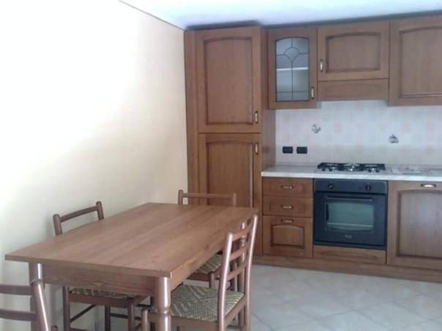 a kitchen with a wooden table and a stove at Le tue vacanze a Varzo, appartamento il girasole. in Varzo