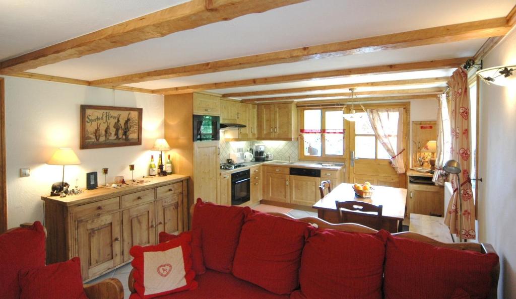 a living room with a red couch and a kitchen at Appart 4 pers proximité lac et remontées Le Praz - Arrayanes in Courchevel