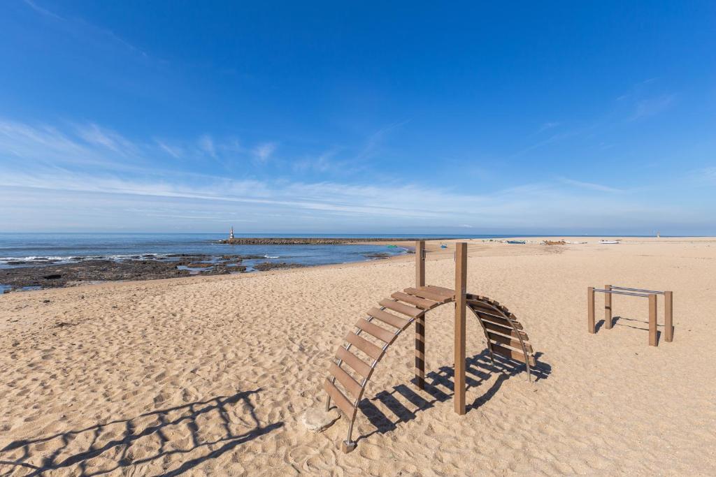 un parque infantil en una playa con el océano en Aguda Beach Porto, Slow Travel Houses en Vila Nova de Gaia