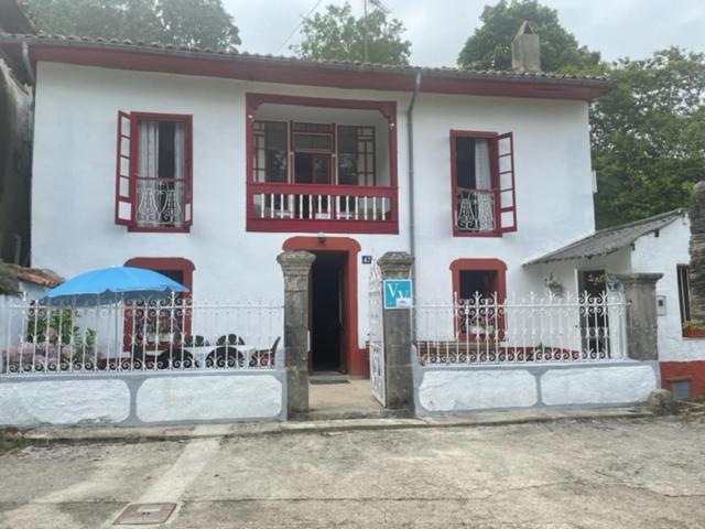 a white house with red windows and a fence at El Requexu de Rales in Rales