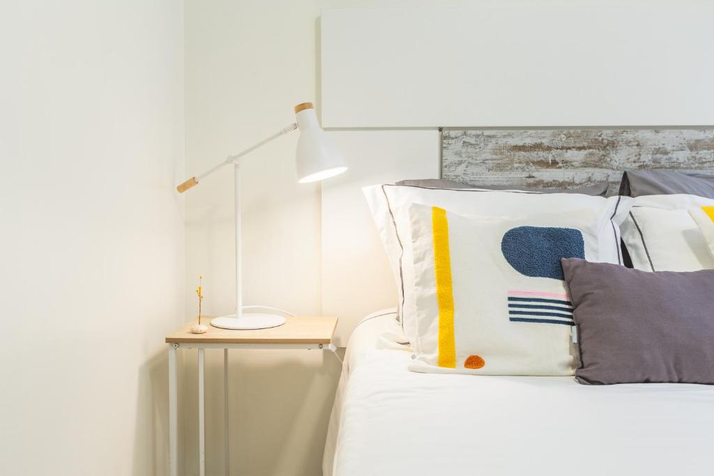 a bedroom with a bed with a lamp and pillows at Aguda Beach Porto, Slow Travel Houses in Vila Nova de Gaia