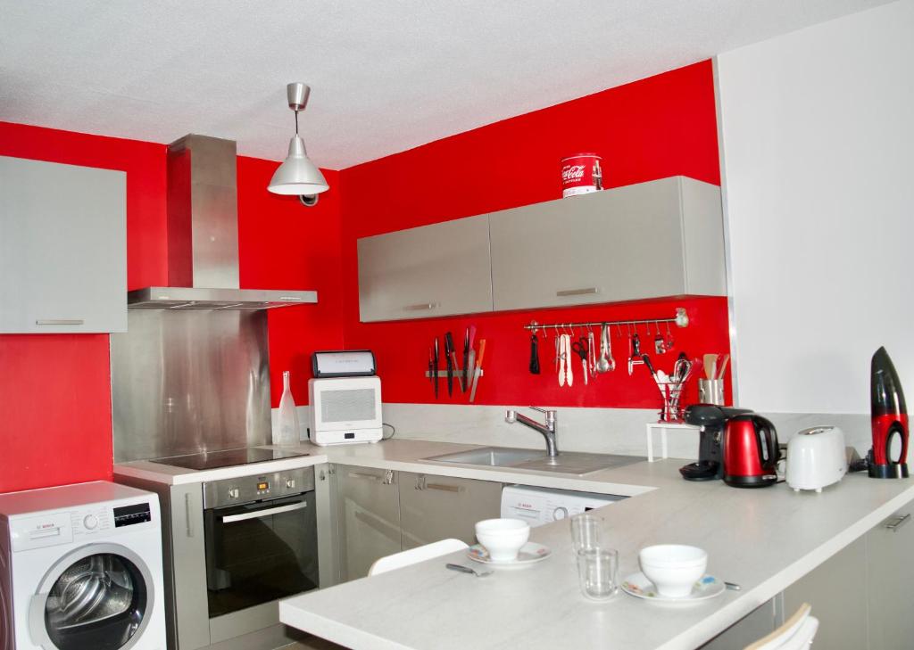- une cuisine rouge avec un évier et un lave-linge dans l'établissement LE PEARL - La grande motte 1er ligne vue mer - climatisation et parking, à La Grande Motte