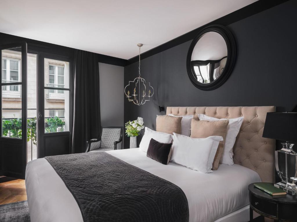 a bedroom with a large bed and a mirror at Maisons du Monde Hotel & Suites - Nantes in Nantes