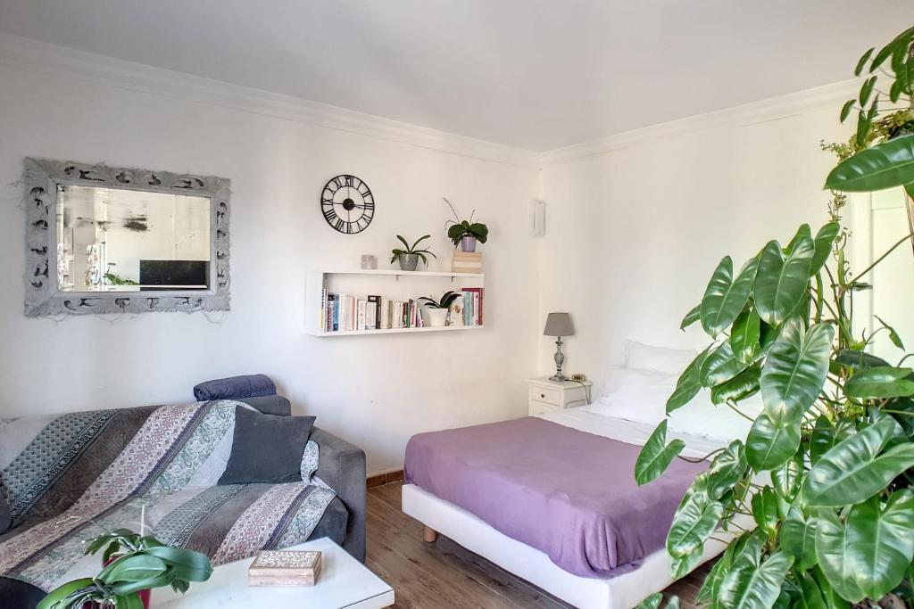 um quarto com uma cama, um sofá e um relógio em HENRI CAMILLE REAL ESTATE - CARNOT - Nice studio 8min Palais em Cannes