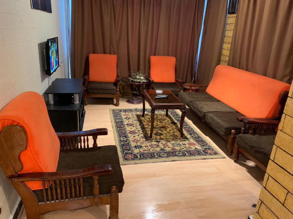 a living room with orange chairs and a couch at Maamoura Beach Zahraa Apartment 9/206 in Alexandria
