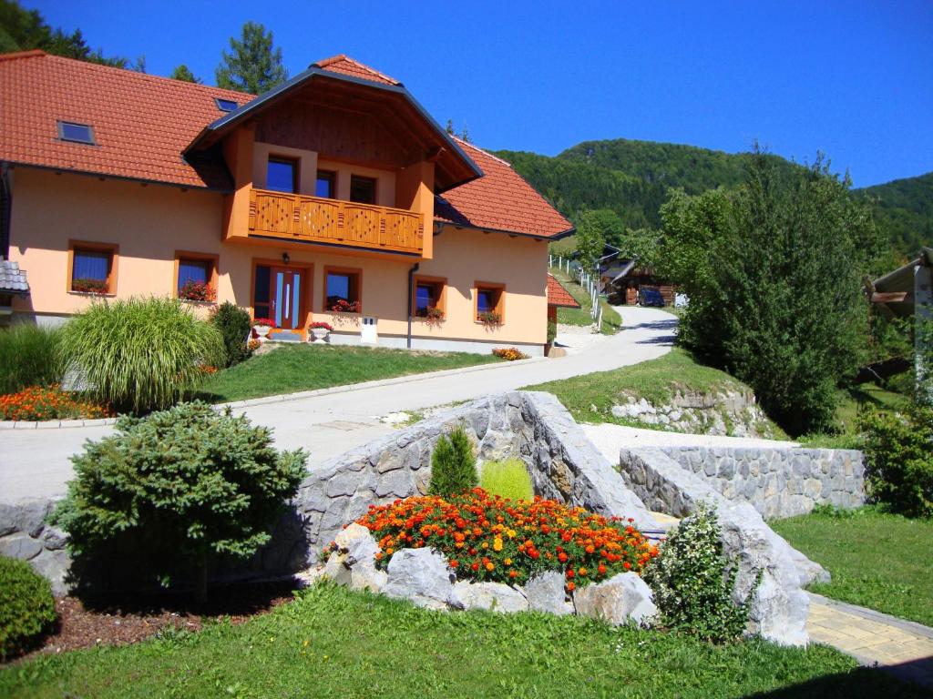 a house with a garden and flowers in front of it at Apartments Trebušak in Laze v Tuhinju