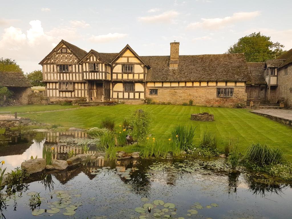 an old house with a pond in front of it at The Threshing Barn at Penrhos Court in Kington