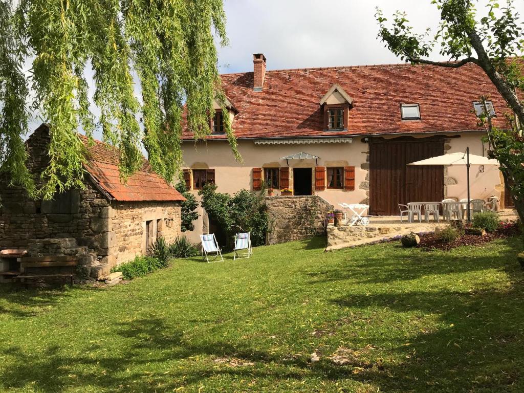 ein Haus mit einem Garten mit Stühlen und einem Sonnenschirm in der Unterkunft Gîte Le Mur magnifique longère au Bourgogne-du-Sud in Oyé