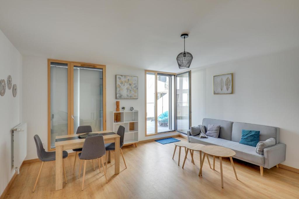 een woonkamer met een bank en een tafel en stoelen bij Chic and spacious apart southern Paris in Massy