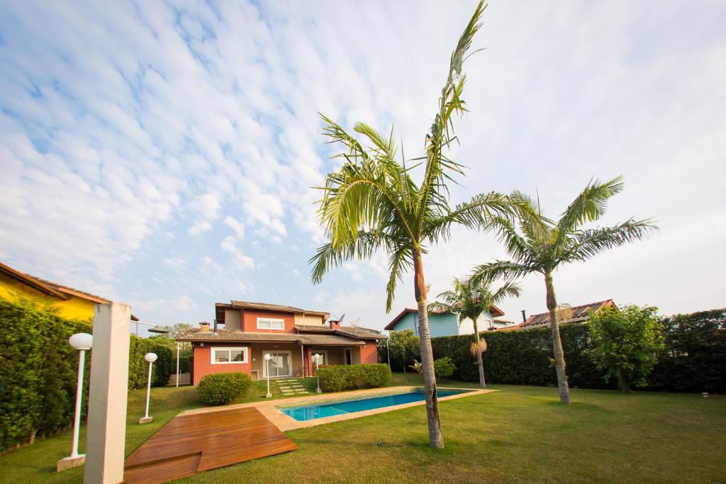 una casa con piscina en un patio con palmeras en Linda Casa de Campo - Próximo à SP - Wi-Fi grátis, en Bom Jesus dos Perdões