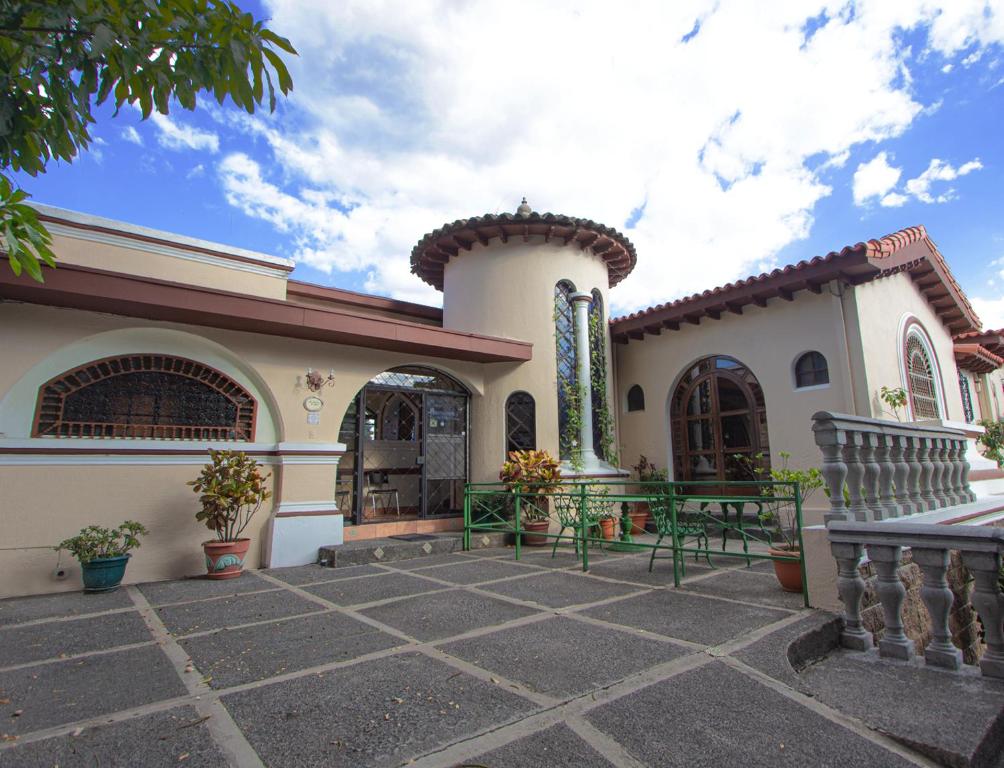 a house with two green benches in front of it at Hotel Villa Serena Escalon in San Salvador