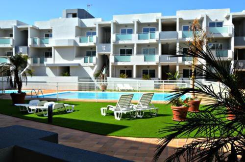 a building with chairs and a swimming pool in front of it at Beautiful, modern apartment in sunny Corralejo in Corralejo