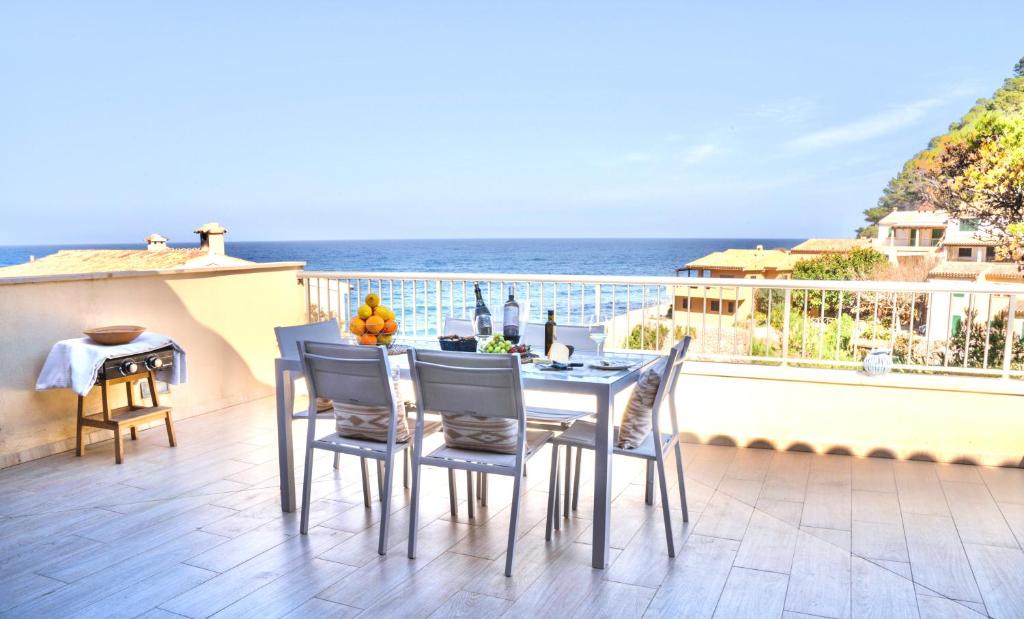 einen Tisch und Stühle auf einem Balkon mit Meerblick in der Unterkunft Can MarSal Puerto Valldemosa in Valldemossa