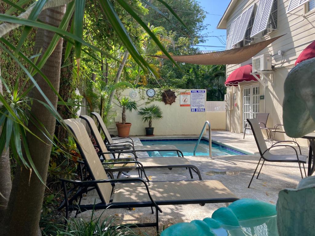 a group of chairs sitting next to a swimming pool at Authors Key West Guesthouse in Key West