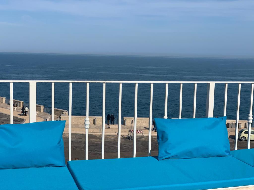 eine blaue Couch auf einem Balkon mit Blick auf den Strand in der Unterkunft Terracielo Home casa vacanza privata in Polignano a Mare