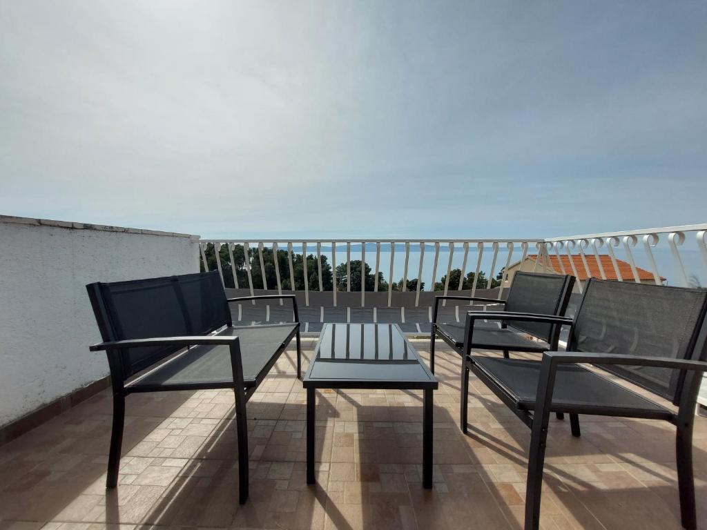 three chairs and a table on a balcony at Apartments Oliva in Podgora