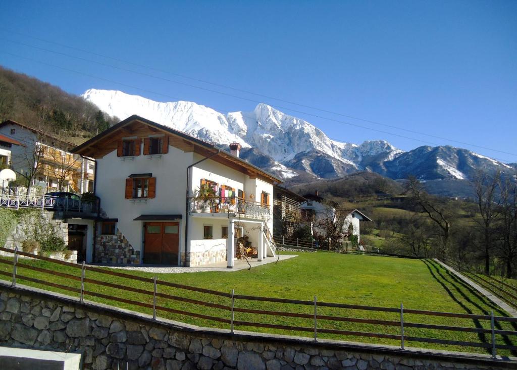 a house with a green yard with mountains in the background at Apartment Šavli in Kobarid
