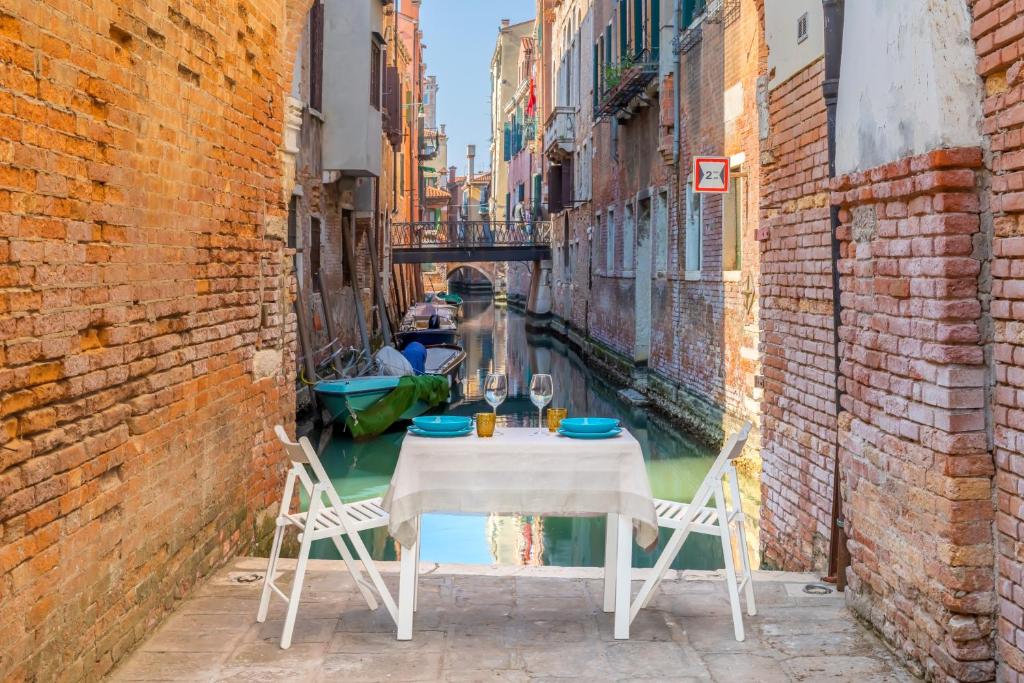 a table and chairs in an alley with a canal at Ramo del teatro Canal view in Venice