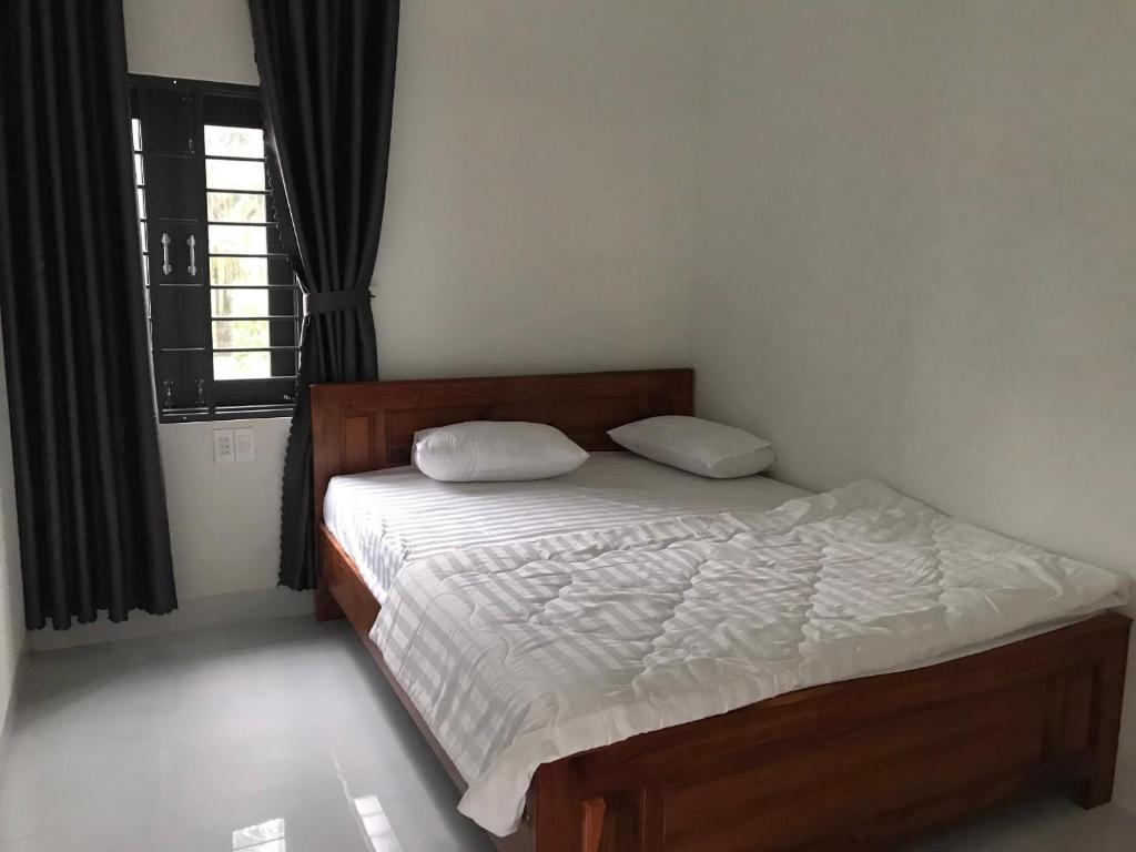 a bedroom with a bed with white sheets and a window at Thanh Tuan Motel in Vinh Hoa