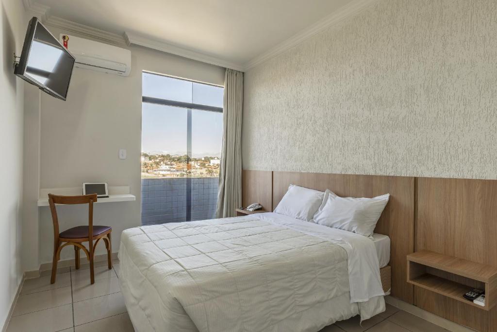 Habitación de hotel con cama y ventana en Hotel Serra Negra en Betim