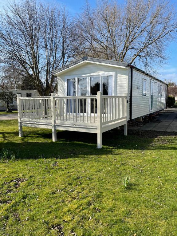 a white house with a porch on a grass field at private rented caravan situated at Southview holiday park in Winthorpe