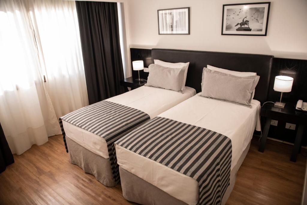 two beds in a hotel room with two lamps at Grand King Hotel in Buenos Aires