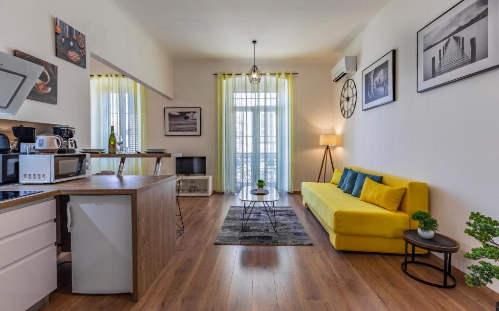 a living room with a yellow couch and a kitchen at Apartment Dream Pula - City Centre in Pula