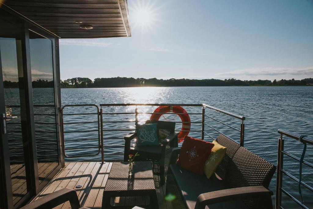 eine Bootsterrasse mit einem Tisch und Stühlen auf dem Wasser in der Unterkunft Domek na wodzie Topiko Czarter - jezioro Mamry in Angerburg