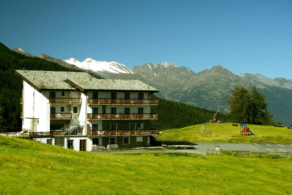 ピーラにあるHotel Chalet des Alpesの山を背景にした丘の上のホテル