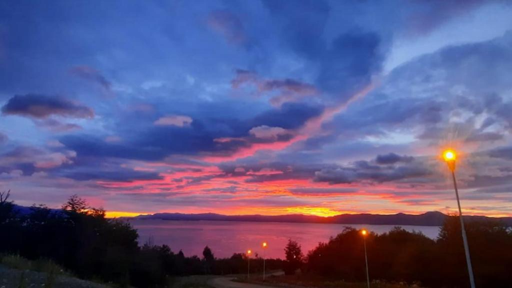 a sunset over a body of water with a street light at Casa Los Ñires Ushuaia in Ushuaia