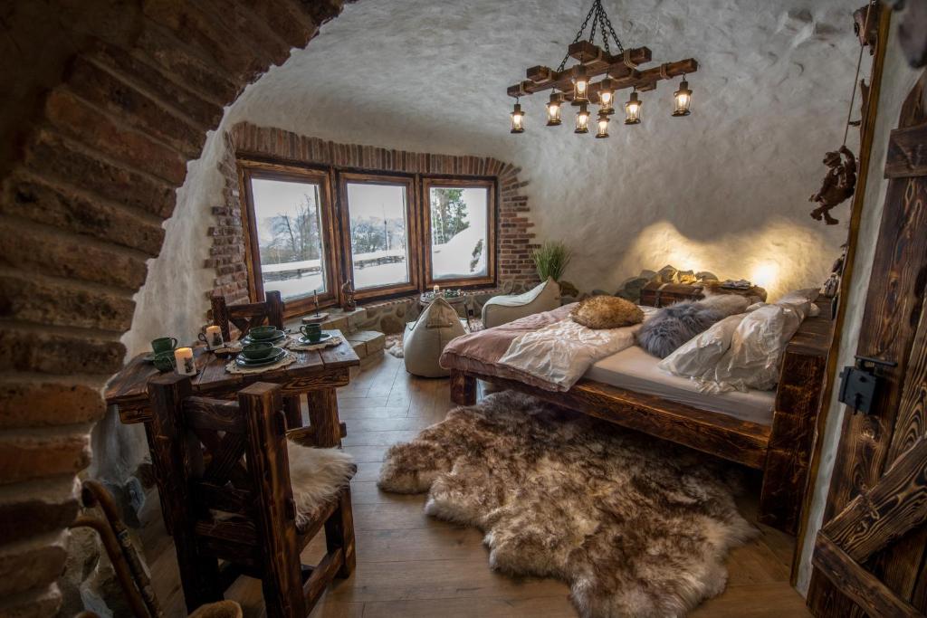 a bedroom with a bed and a table and windows at Osada Jaworzyny - Domek Hobbita z jaskinią SPA in Tokarnia