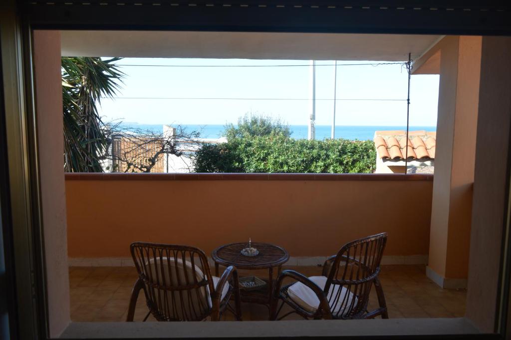 balcón con mesa, sillas y vistas al océano en Casa della Salsedine, en S'Archittu