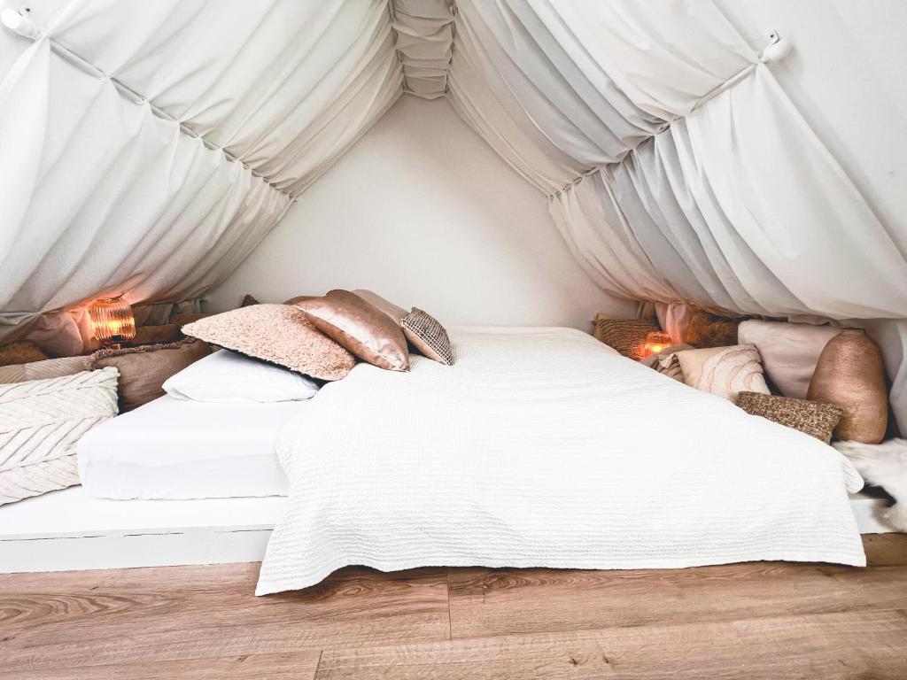 uma cama num quarto com lençóis brancos e almofadas em Catharine Suite em Breda