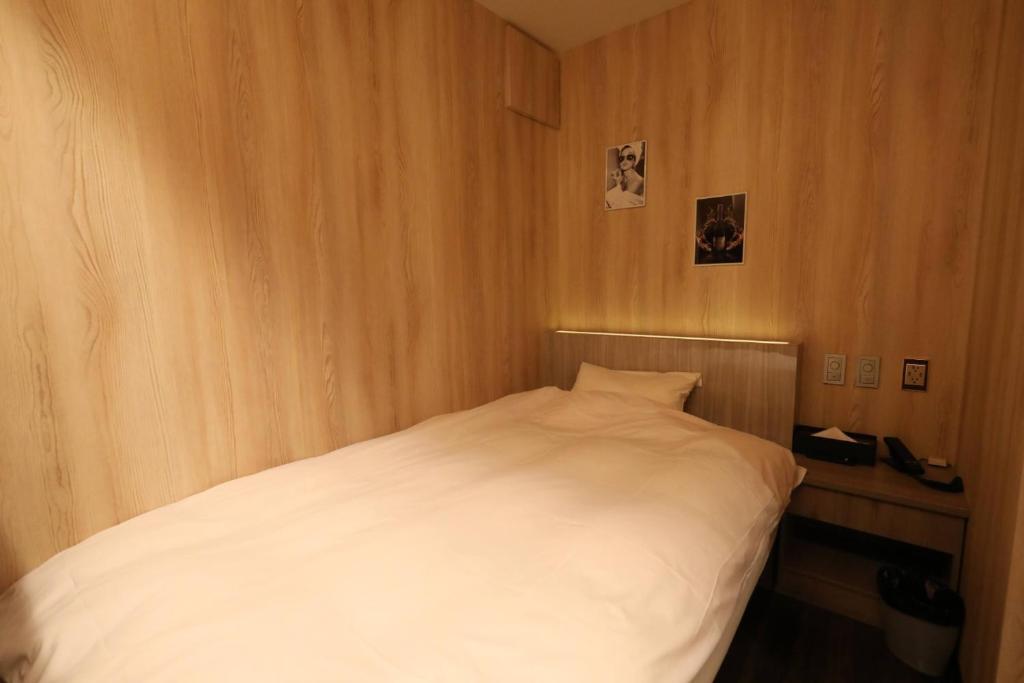 um pequeno quarto com uma cama branca em Takahashi Building 3rd and 4th floors - Vacation STAY 24477v em Musashino