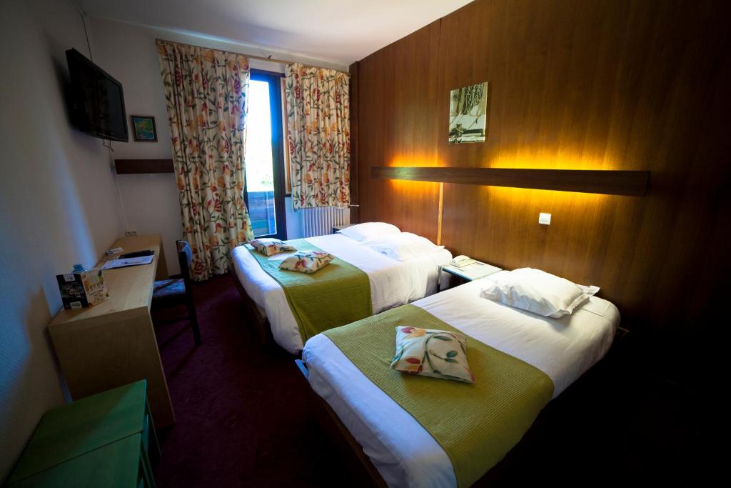 een hotelkamer met 2 bedden en een raam bij Le Grand Hôtel de Besse in Besse-et-Saint-Anastaise