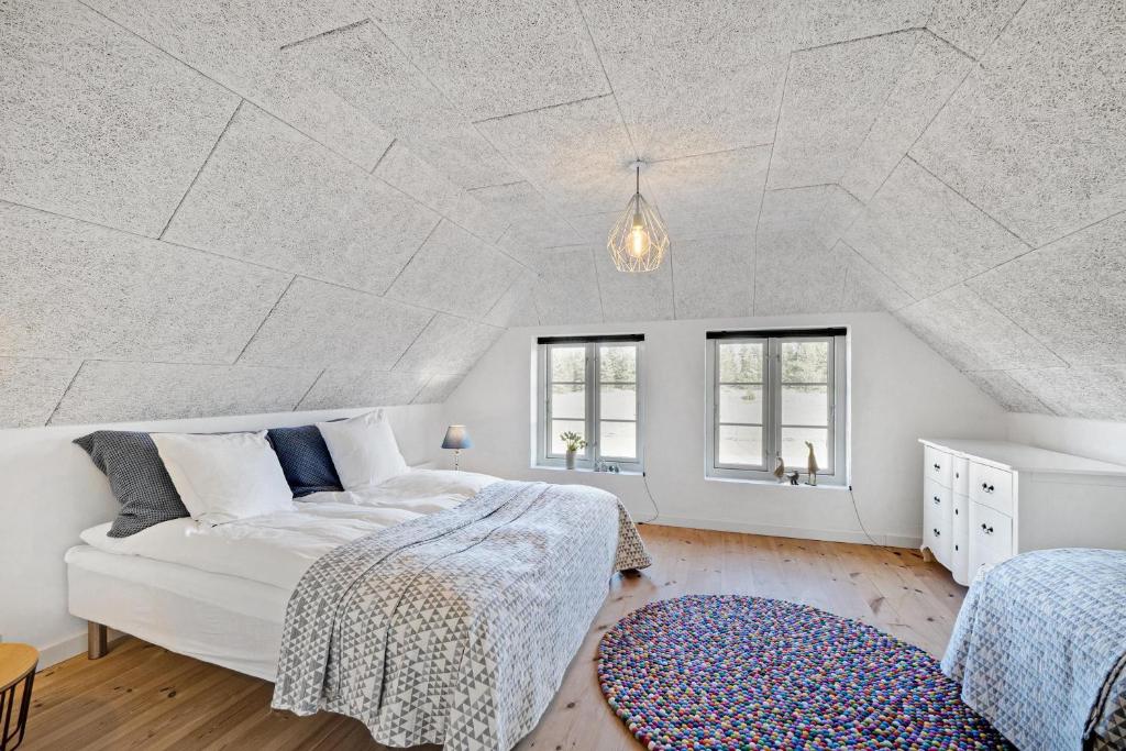 a white bedroom with a bed and two windows at Lildgaard in Frøstrup