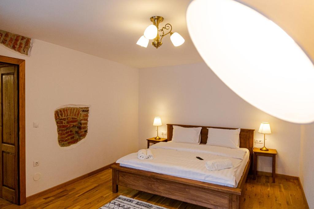 ein Schlafzimmer mit einem Bett mit weißer Bettwäsche und zwei Lampen in der Unterkunft Stone Way Apartment in Sibiu