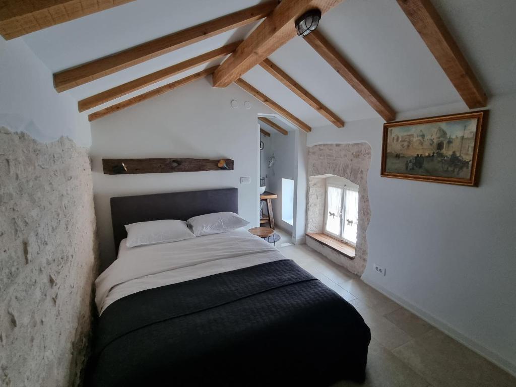 una camera con un grande letto in una stanza con soffitti in legno di Apartmani Ulika a Bale (Valle)