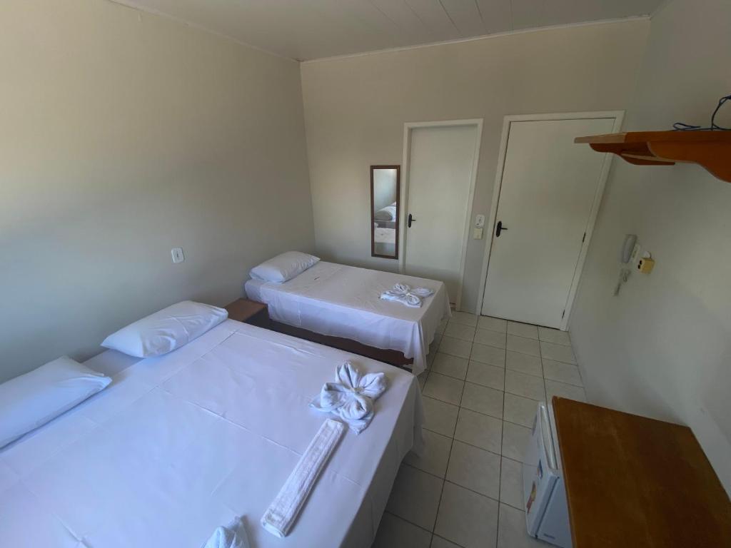 a small room with two beds and a bathroom at Hotel Bianchi in Primavera do Leste