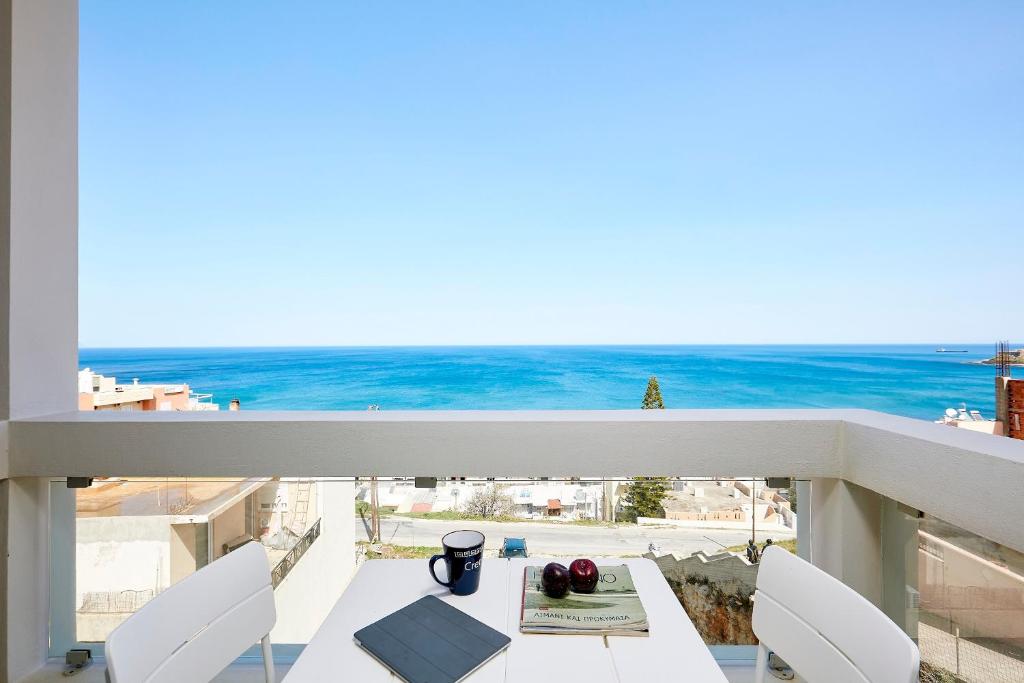 een balkon met een tafel en stoelen en de oceaan bij VIVIAN Art Apartments in Rethimnon