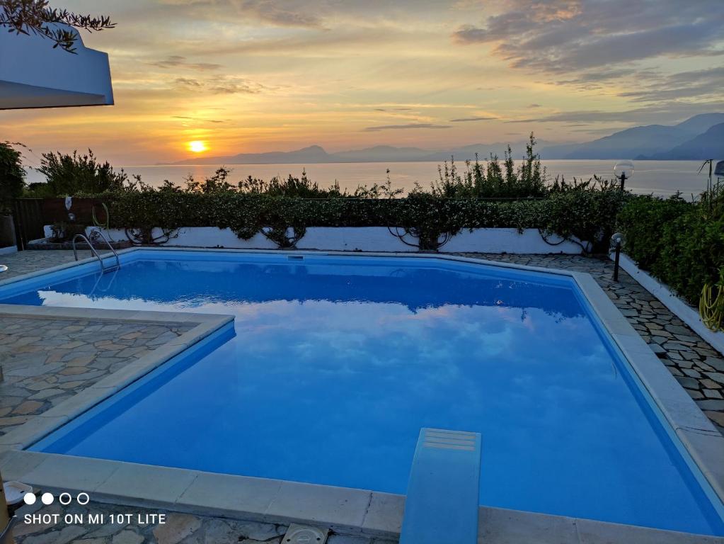 une piscine bleue avec un coucher de soleil en arrière-plan dans l'établissement Villa Max, à San Nicola Arcella