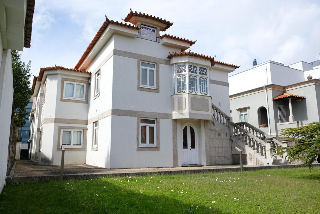 ein weißes Haus mit einer Uhr darüber in der Unterkunft Boavista Studio 99 & Garage in Porto