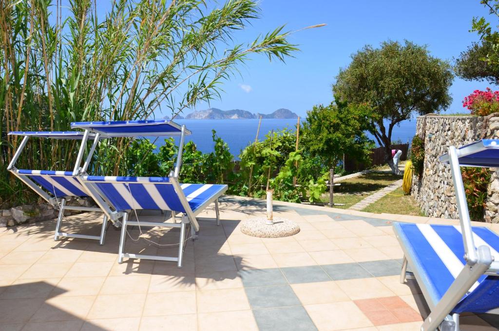 un patio con sillas azules y vistas al agua en Sunset Village Ponza, en Ponza