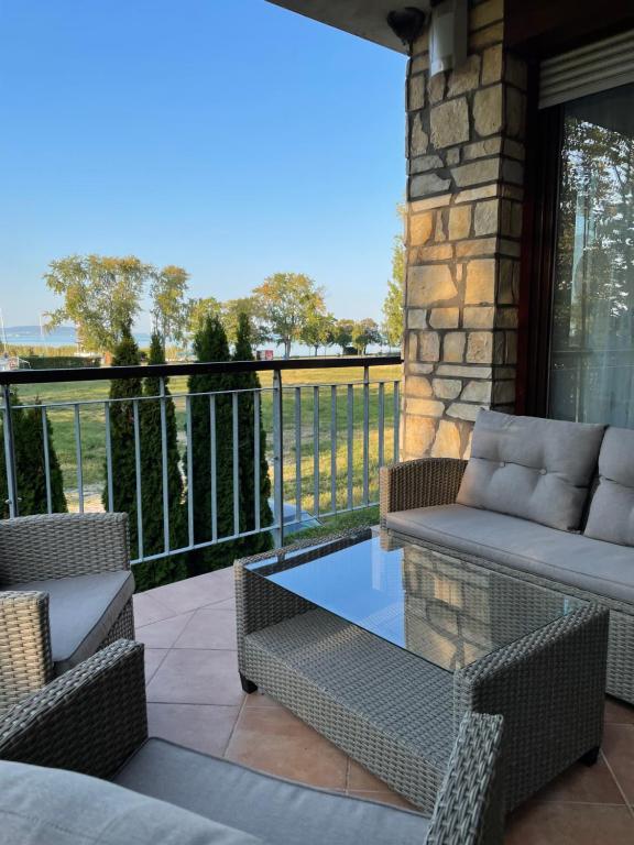 a patio with wicker chairs and a table on a balcony at D-S Apartman Stella in Zamárdi