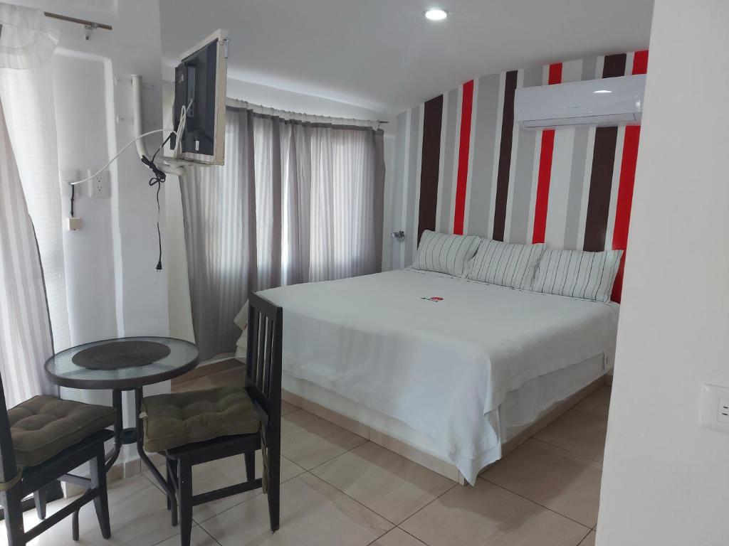 1 dormitorio con 1 cama blanca, mesa y sillas en EL ANCLA, en Ciudad del Carmen